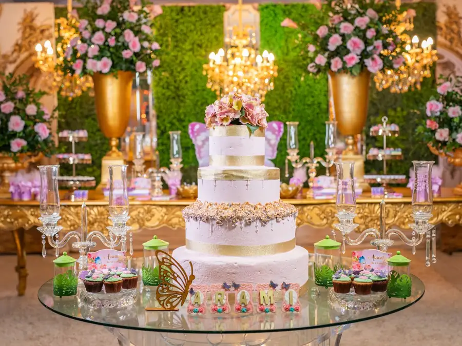 Grand gâteau d'anniversaire sur une table dorée entourée de compositions florales